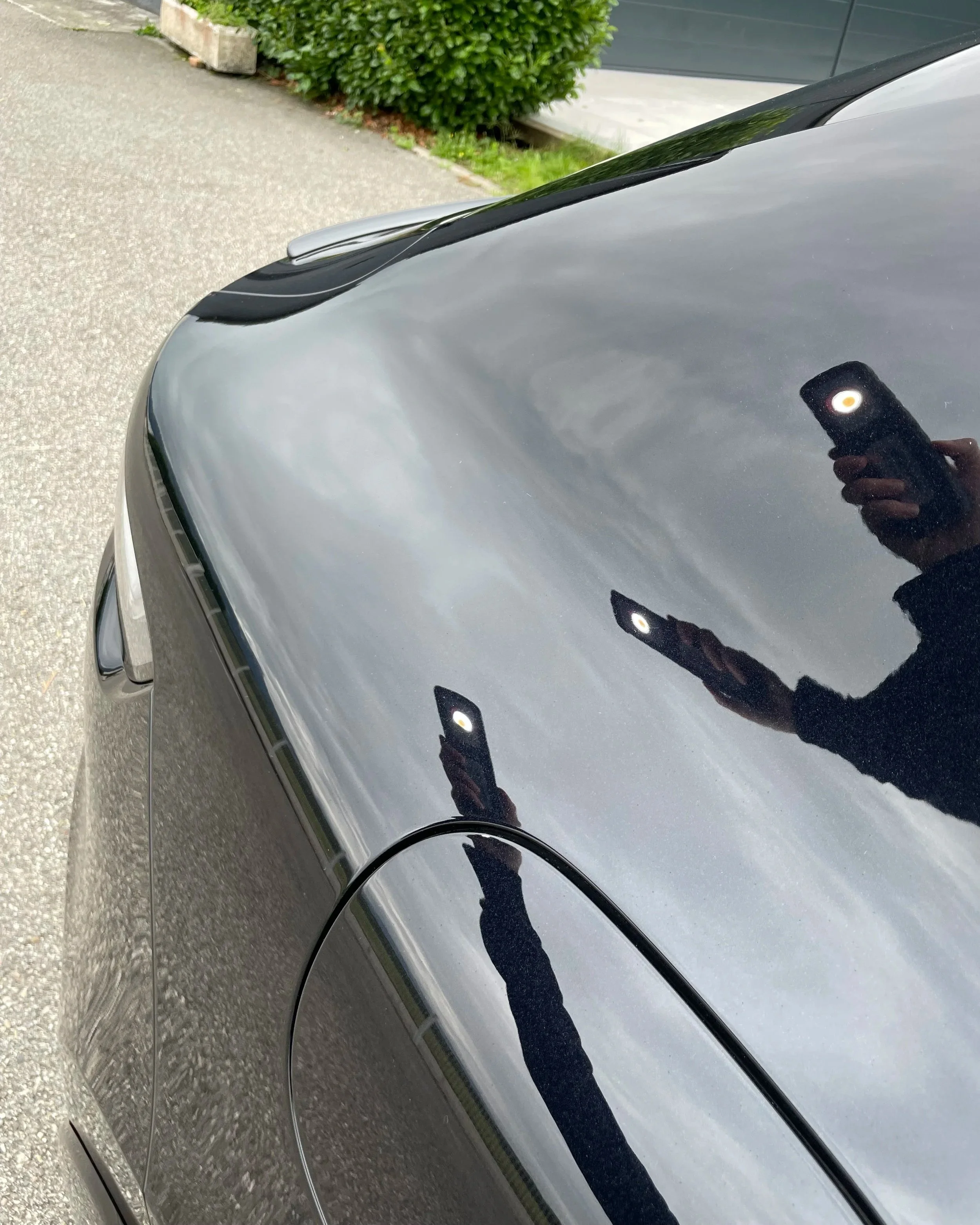 Reflet de deux lampes LED et d'une personne prenant la photo avec un téléphone sur la surface brillante et sombre d'une voiture.
