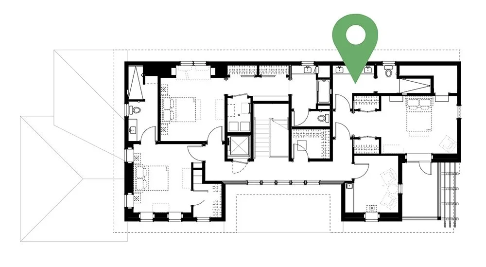 Floor plan of a house with a green location marker near the top right corner, showing various rooms, hallways, and stairs.