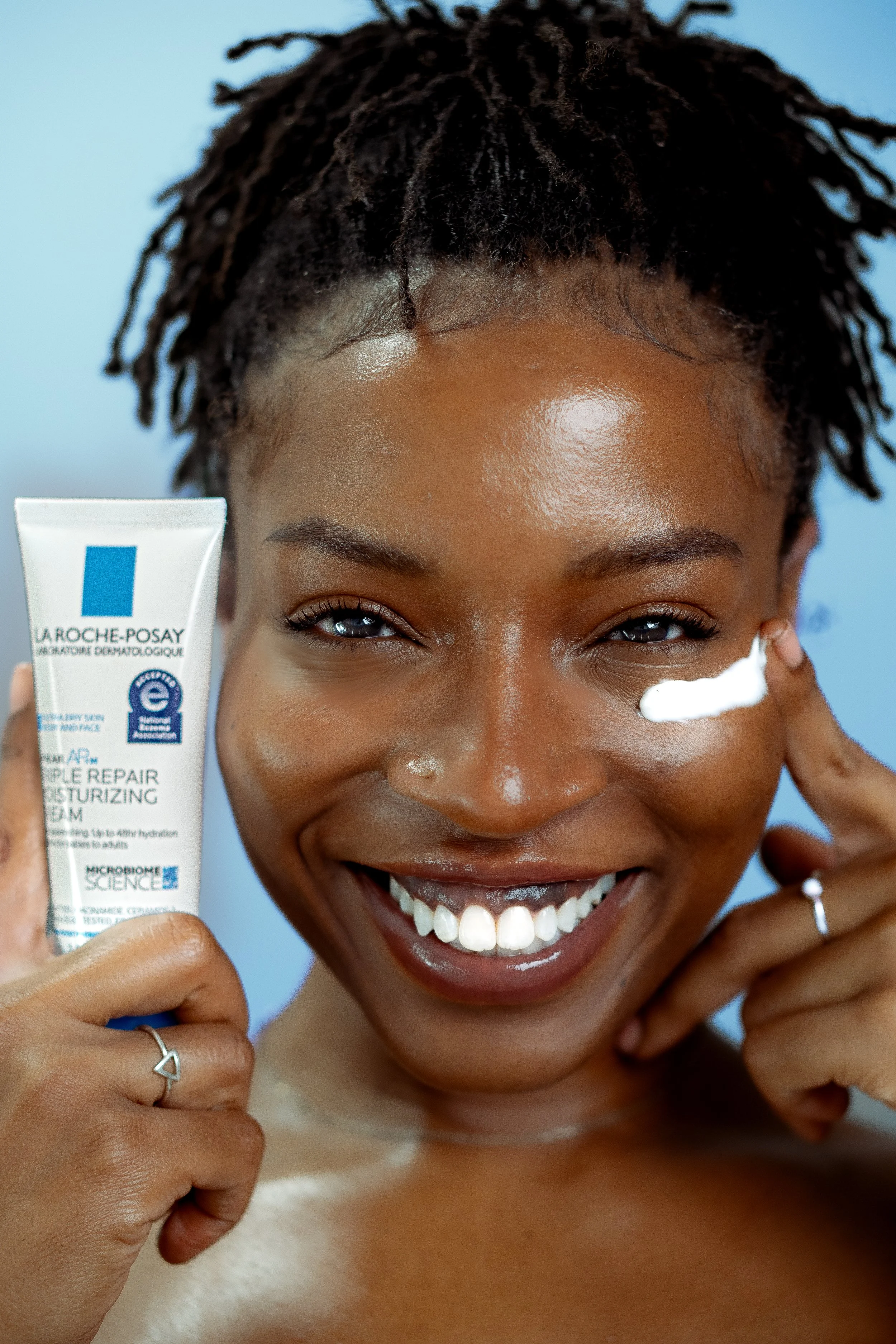 African American Beauty model applying LaRoche Posay moisturizer while smiling.jpg