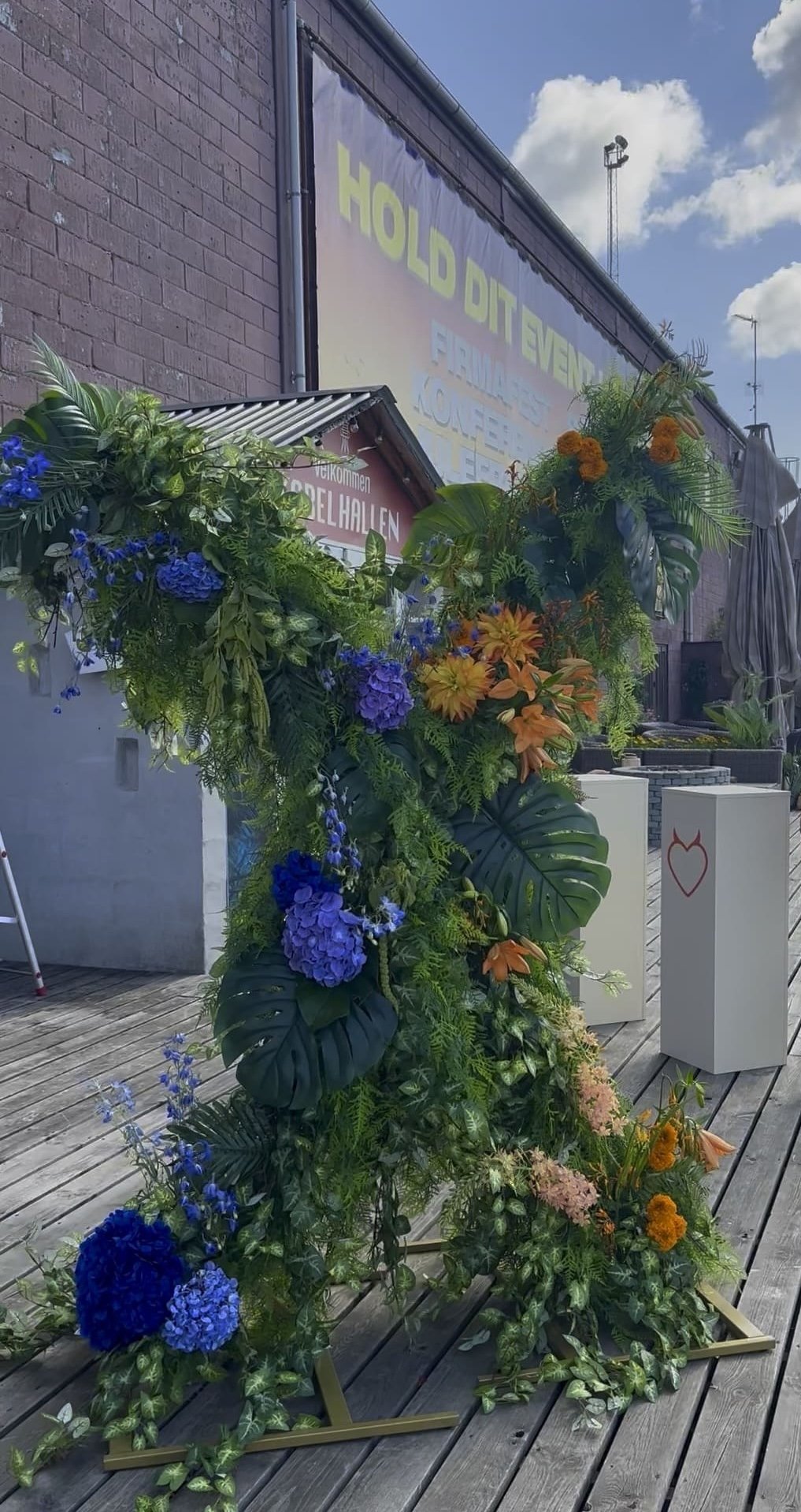 Eksotisk eventstyling med blå og orange blomster og tropiske planter til Temptation Island Danmark.