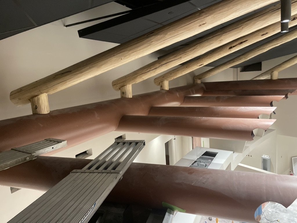 Interior of a building under construction with large wooden beams and a metal ladder.