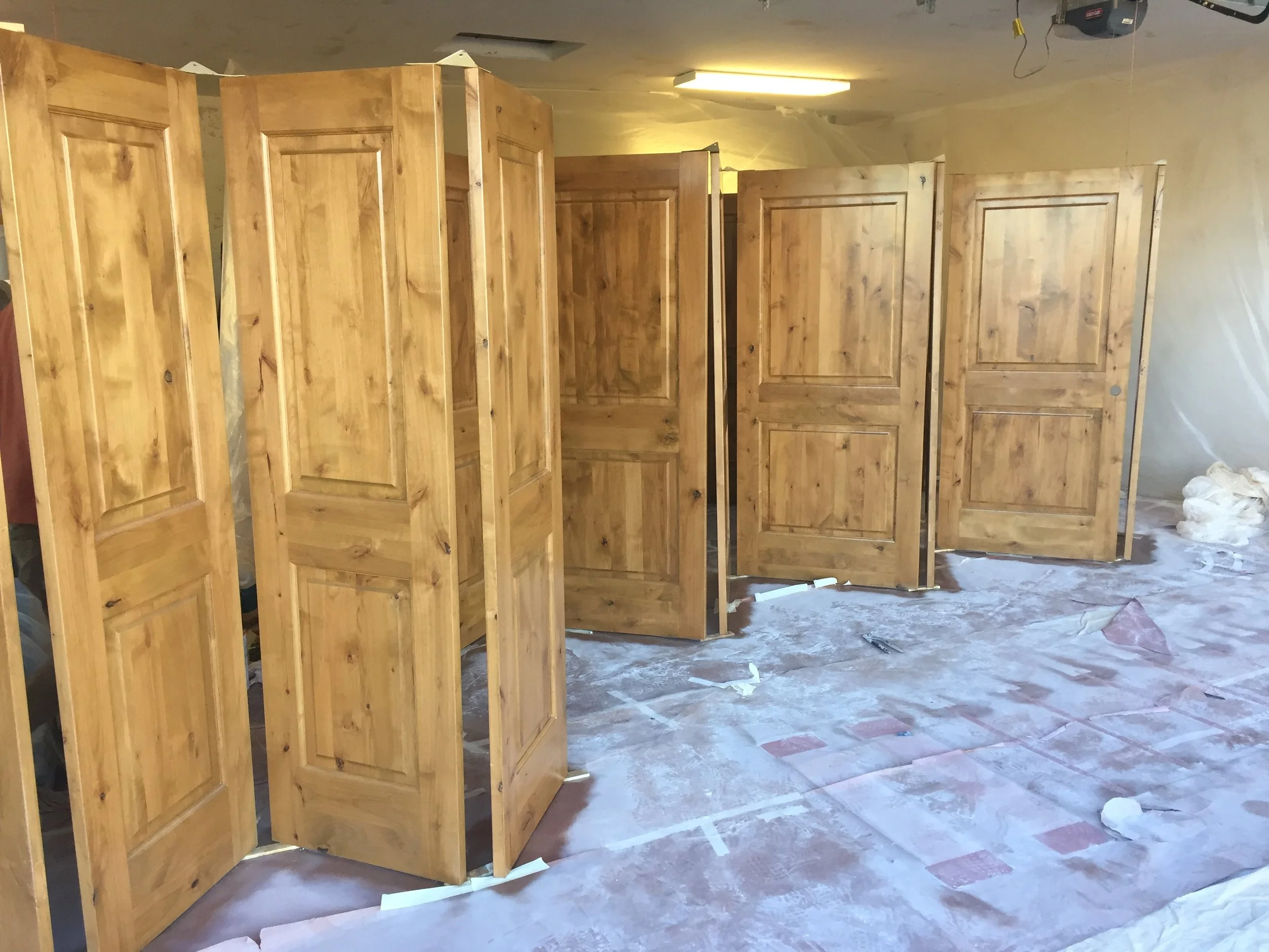 A room under construction with partial wooden wall panels and a garage door opener attached to the ceiling.