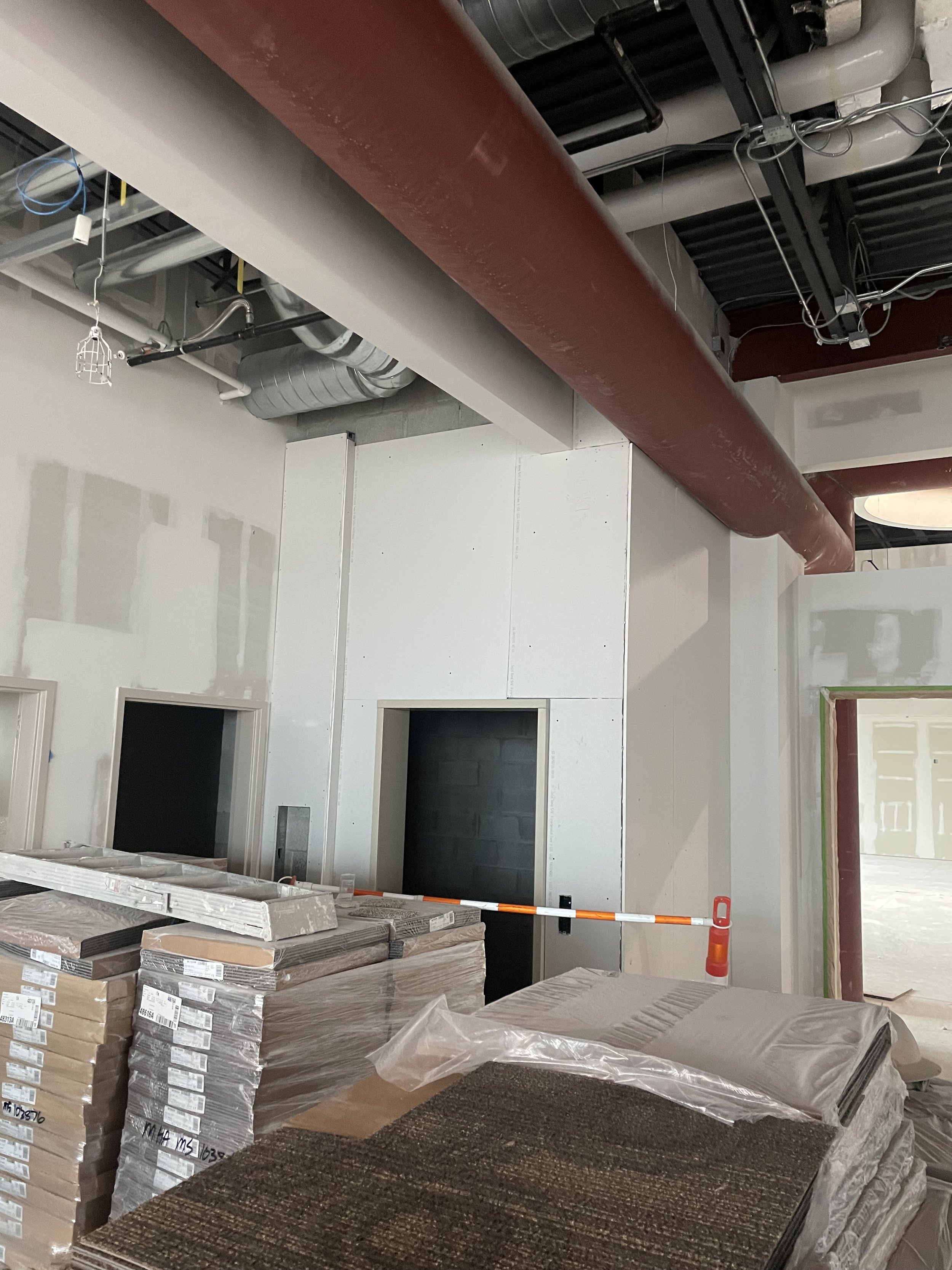 Construction site with stacked tiles, insulation, and partially finished drywall.