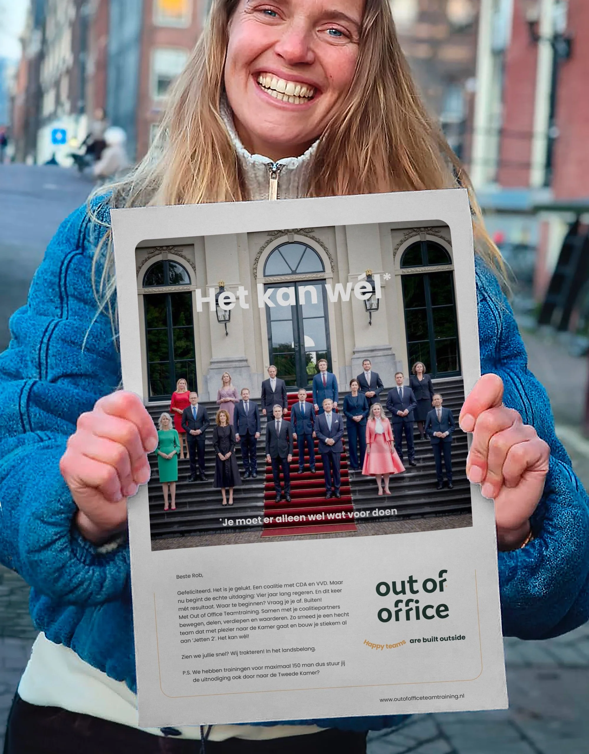 Vijf mensen zitten op een zandheuvel met gras, lachen en praten.