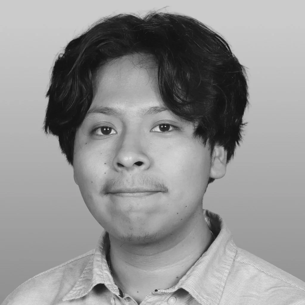 Black and white portrait of a young man with wavy hair, light facial hair, and a collared shirt.