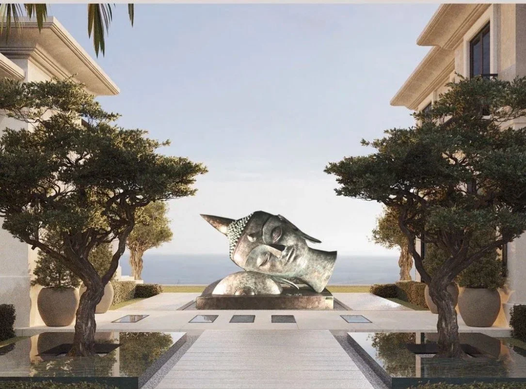Reflective metal sculpture between two trees overlooking the sea