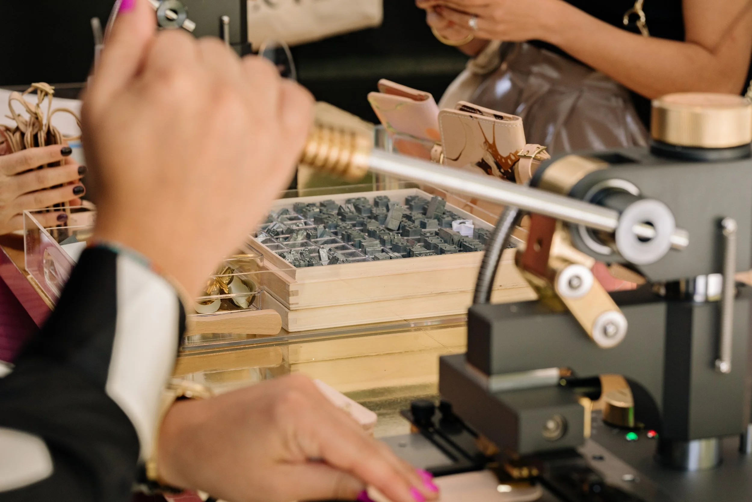 Hands operating a hot foil embossing machine with metal types for customization.