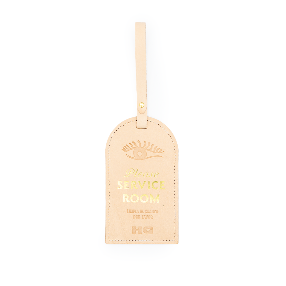 A beige room service door hanger with 'Please Service Room' text and an eye illustration.