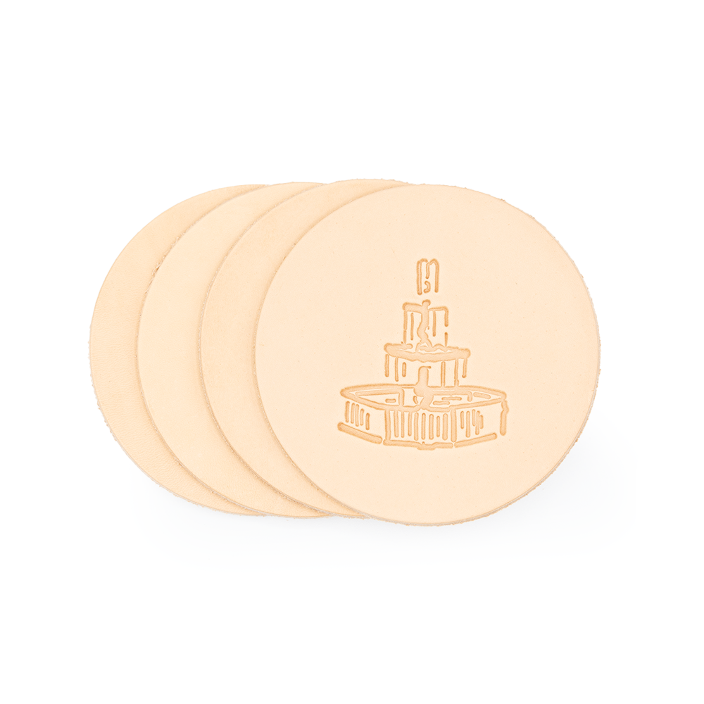 Four round, beige leather coasters with a water fountain design embossed on them, stacked slightly overlapping.