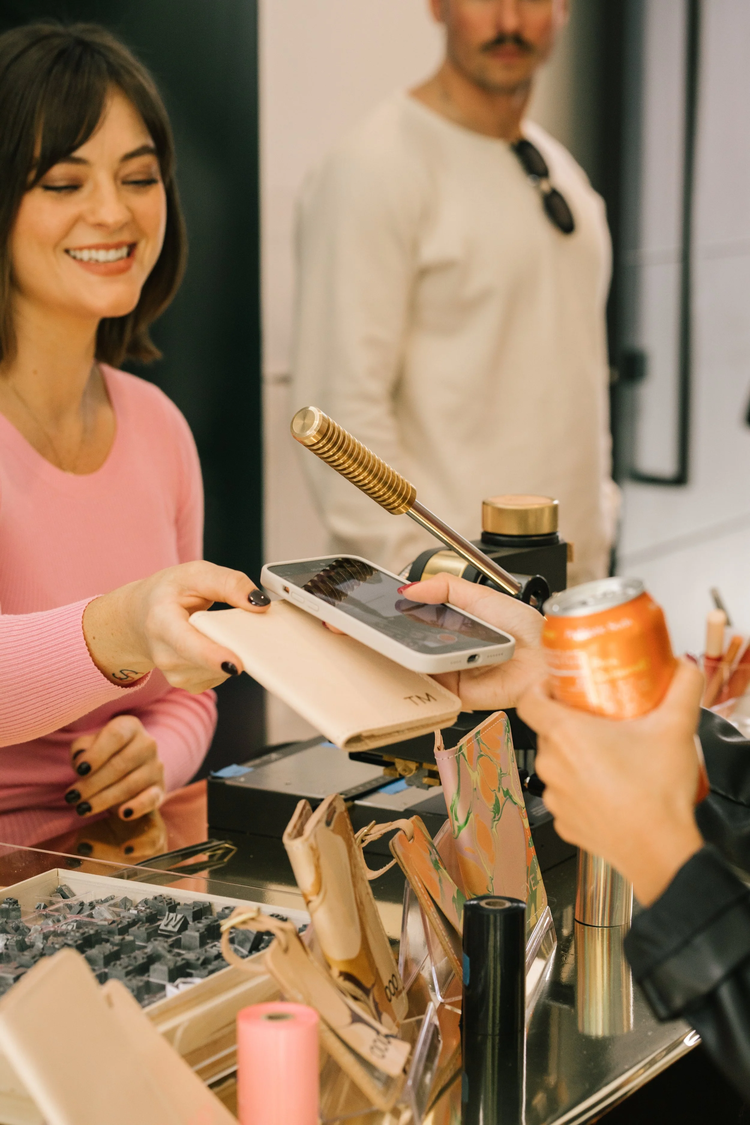 Woman handing customized leather item to event attendee.