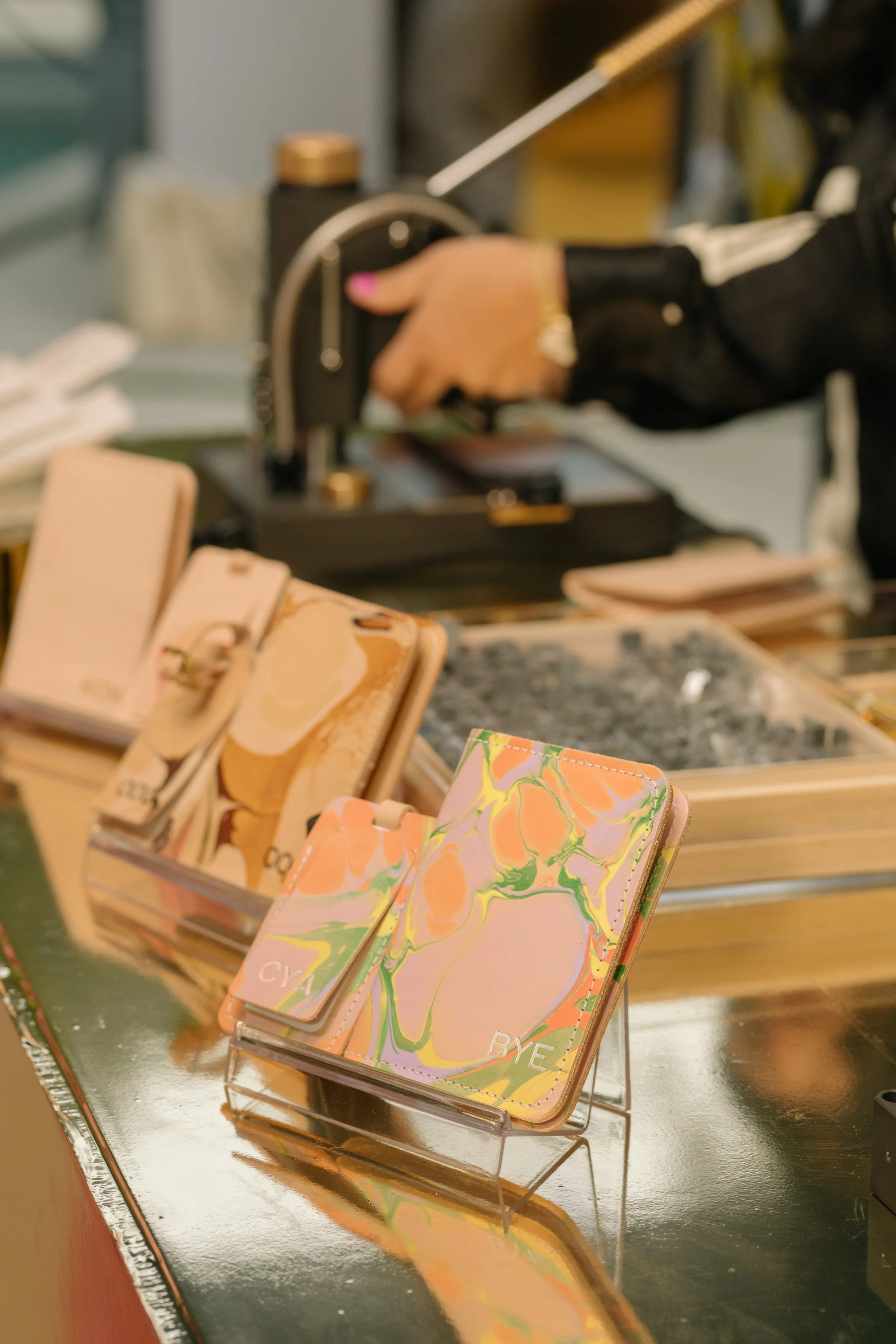 Colorful leather goods displayed with someone using hot foil press to emboss the background. 