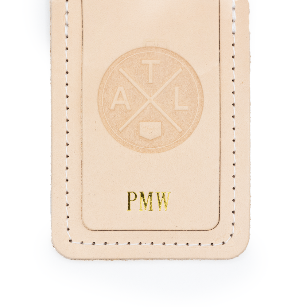 Beige leather tag with "ATL" circle logo embossed and "PMW" in gold letters
