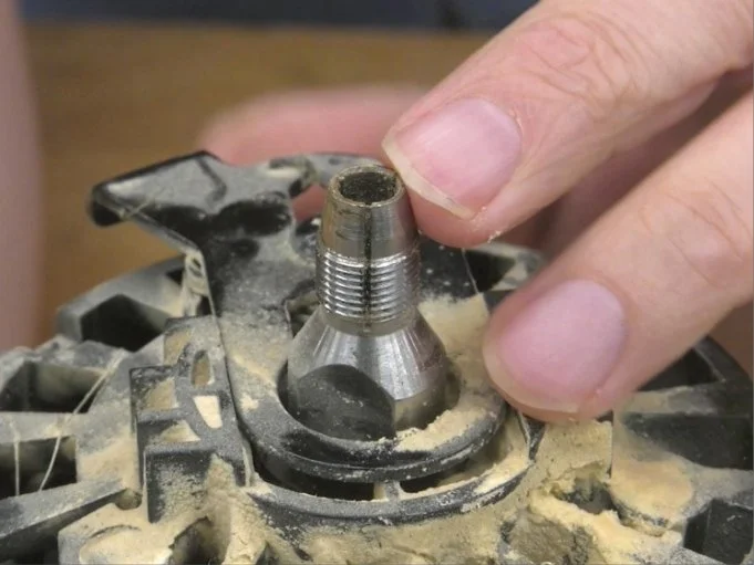 a finger pointing at the top edge of a collet that is integrated directly into the motor of a router