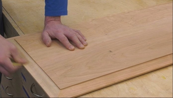 a person's hands on a wooden panel with raised edges