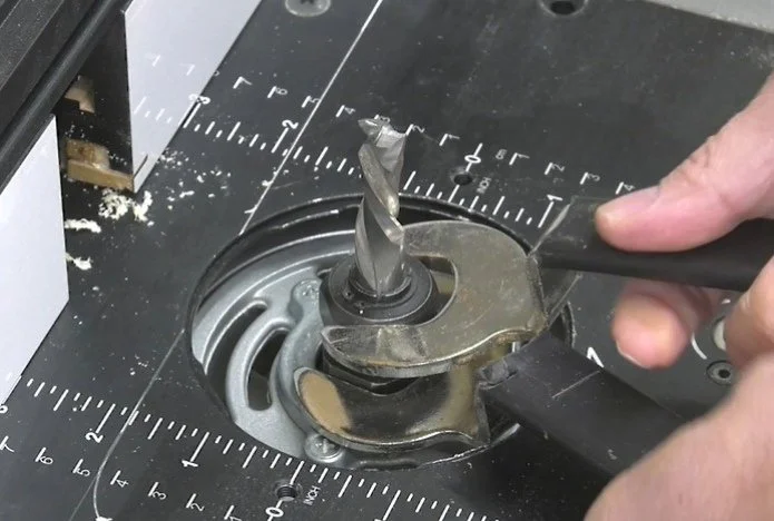 two hands using two wrenches to loosen a router collet nut