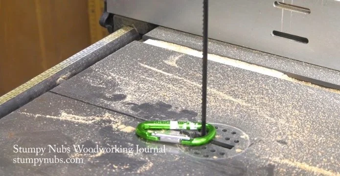 a carabiner clipped around the bandaw blade to indicate the blade tension is released