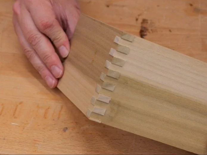 two wood pieces fit together with unfinished box joints staged on a wooden table top