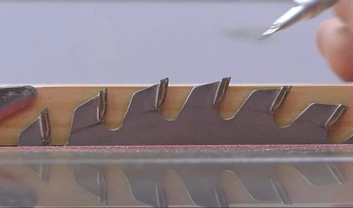 a table saw blade just above a piece of wood