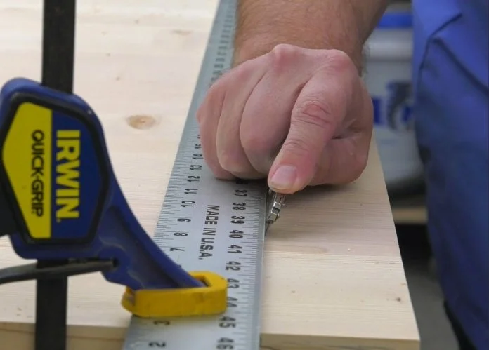 severing wood fibers along the straight edge of a ruler that is clamped down