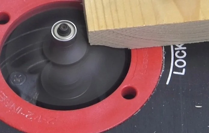 the end of a wooden board being cut by a spinning router bit
