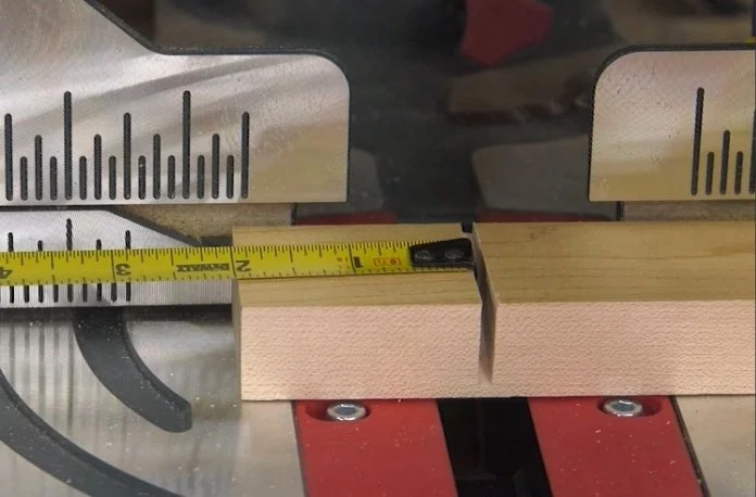 a board clamped to the top of a miter saw with the end of a measuring tape hooked on.