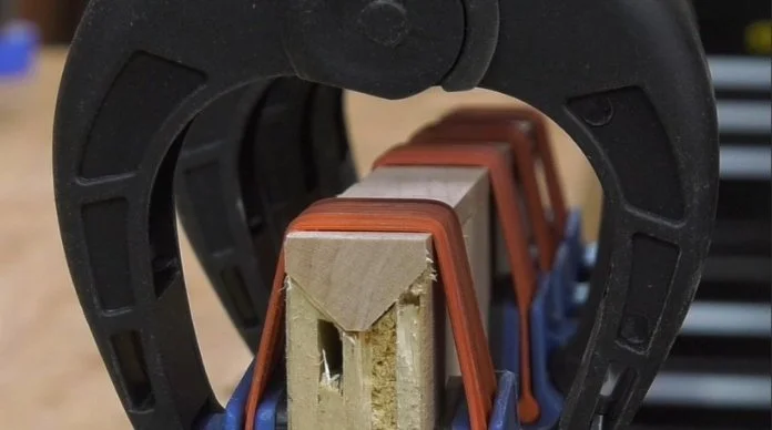 gluing the hardwood edge banding to the plywood piece. Held down using clamps