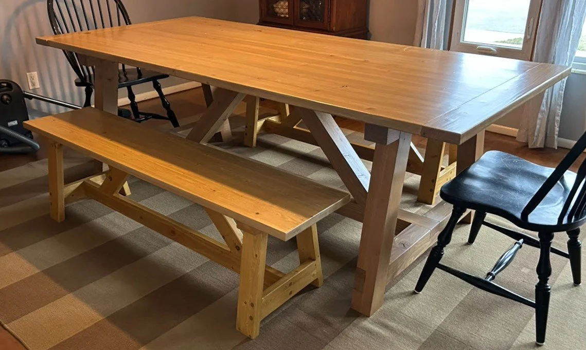 a finished dining room table with finished benches and 2 black chairs