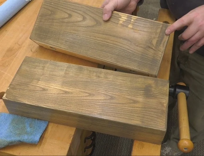 thing coat of stain on a piece of wooden project, sitting on top of a bench