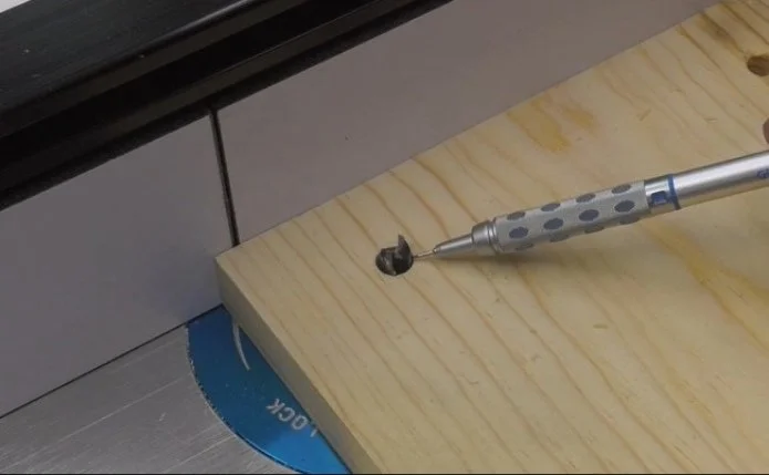 a pilot hole in a piece of wood created with a drill press that fits over the router bit in a router table