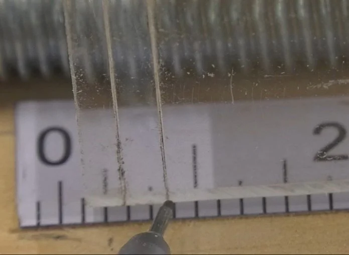 a pencil pointing at one of two lines etched on a piece of acrylic that align with 1/8"