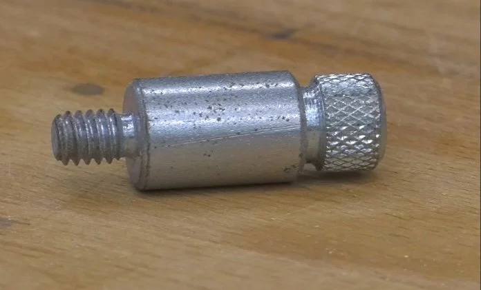 A router table starter pin laying on a wooden bench top