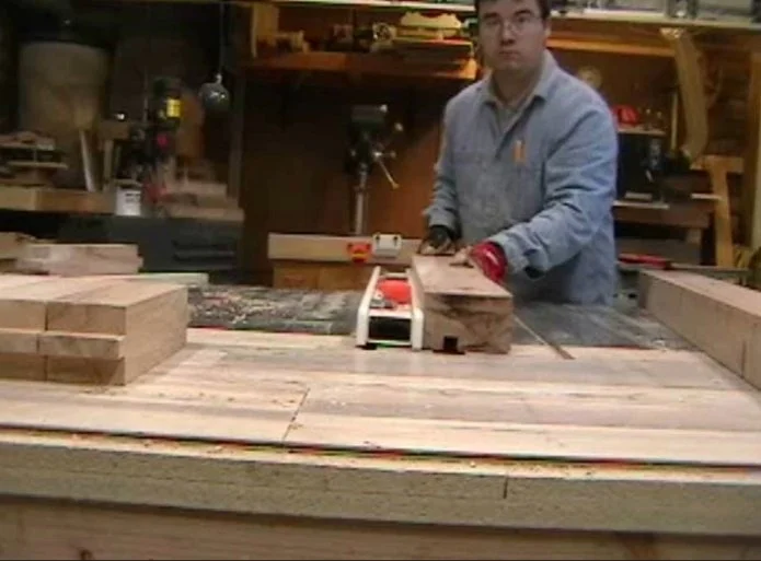 a man cuting a piece of wood on a table saw
