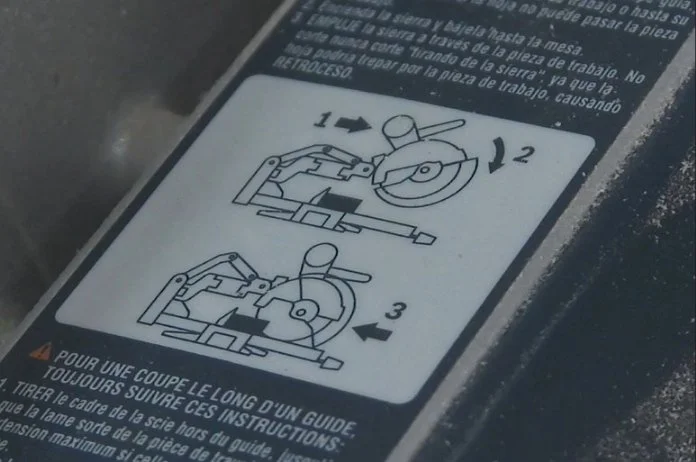 a line drawing sticker showing how the proper miter saw cutting technique is to pull the  saw out, lower, and push the blade away from you.
