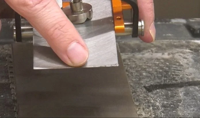 a burr that has formed over the back edge of a plane iron with a diamond stone underneath in the background