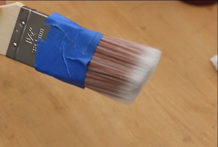 blue painter's tape wrapped around the paint brush to keep finish from soaking too far into the roots for easier cleaning