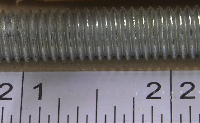 a close up of how a 3/8 16 thread pattern of a bolt corresponds to the 16ths of an inch on a ruler