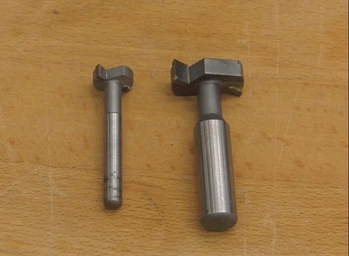 a small and a large t-slot router bits sitting on top of a wooden table top