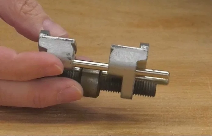 a hand holding an eclipse-style sharpening jig over a wooden bench top
