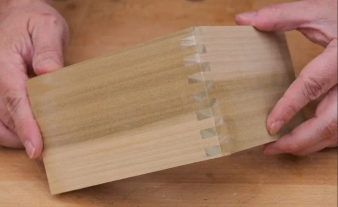 two hands holding up a corner joint that utilizes box joints