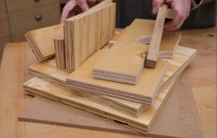 a pile of scrap wood that will be used to make a diy portable router table, sitting on top of a wooden work bench