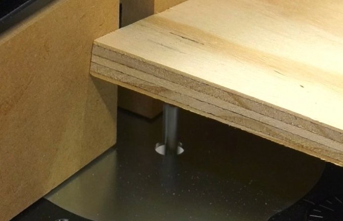 easing a piece of plywood down onto a spinning router bit in a router table