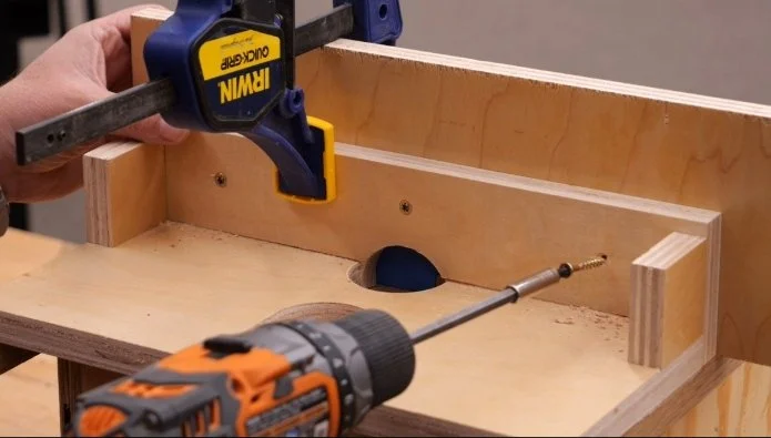 using a rigid drill to screw a plywood panel to a diy router fence that is clamped down