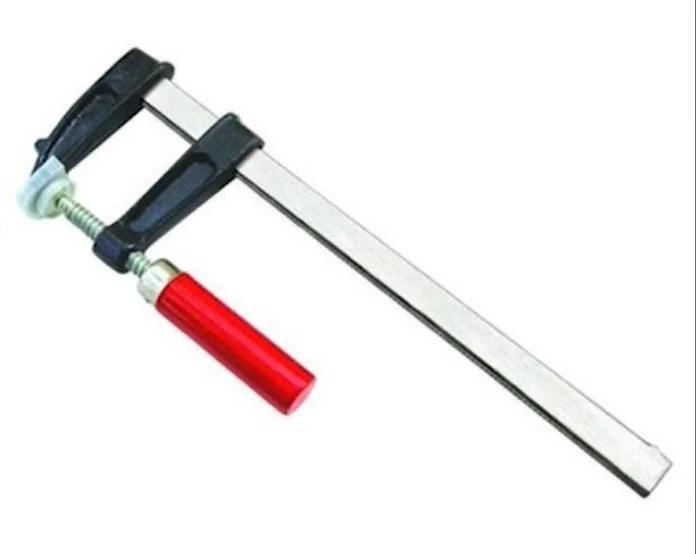 a metal f clamp with black jaws and a red handle on a white background