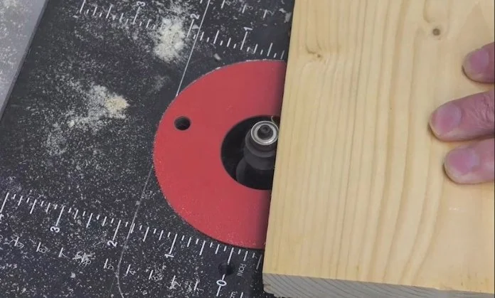 freehand routing on a router table where the bearing of the router bit is guiding the wooden work piece through the cut