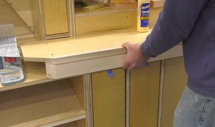 hands adding homemade t track out of wood to a miter saw station