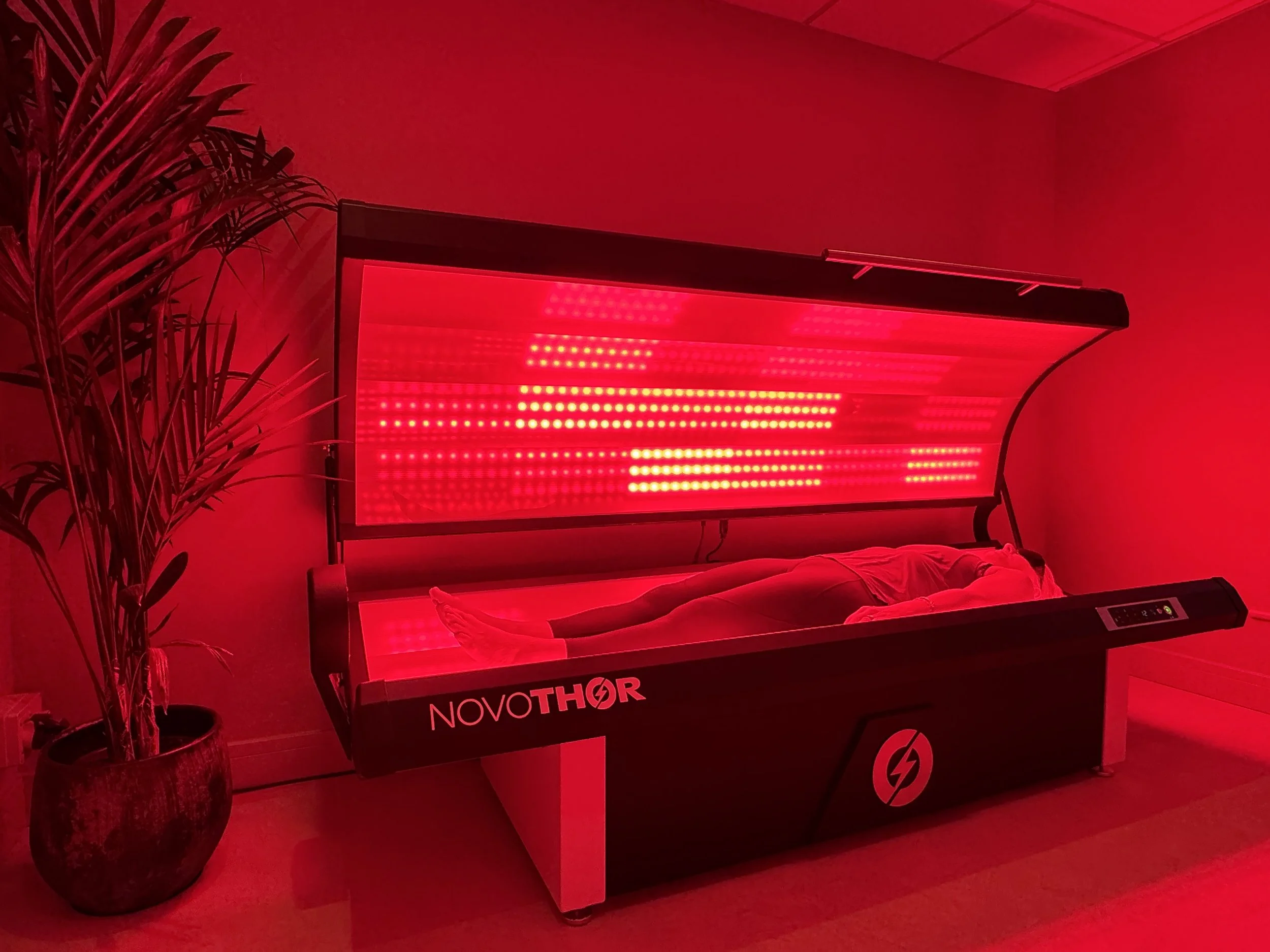 Client undergoing whole-body red light therapy in a NovoTHOR bed at ReGen Rooms wellness clinic.