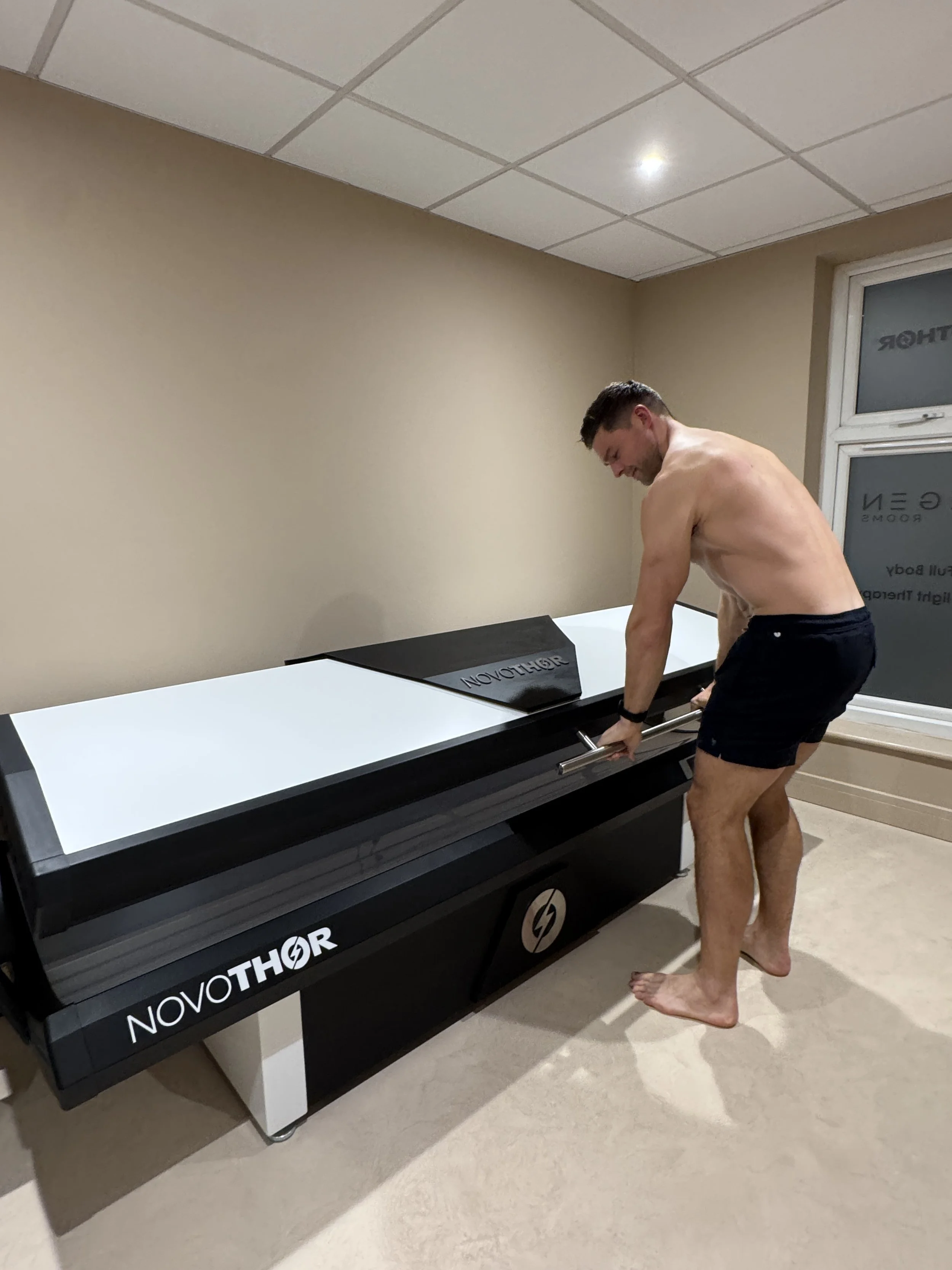 Practitioner preparing the NovoTHOR XL red light therapy bed for a session