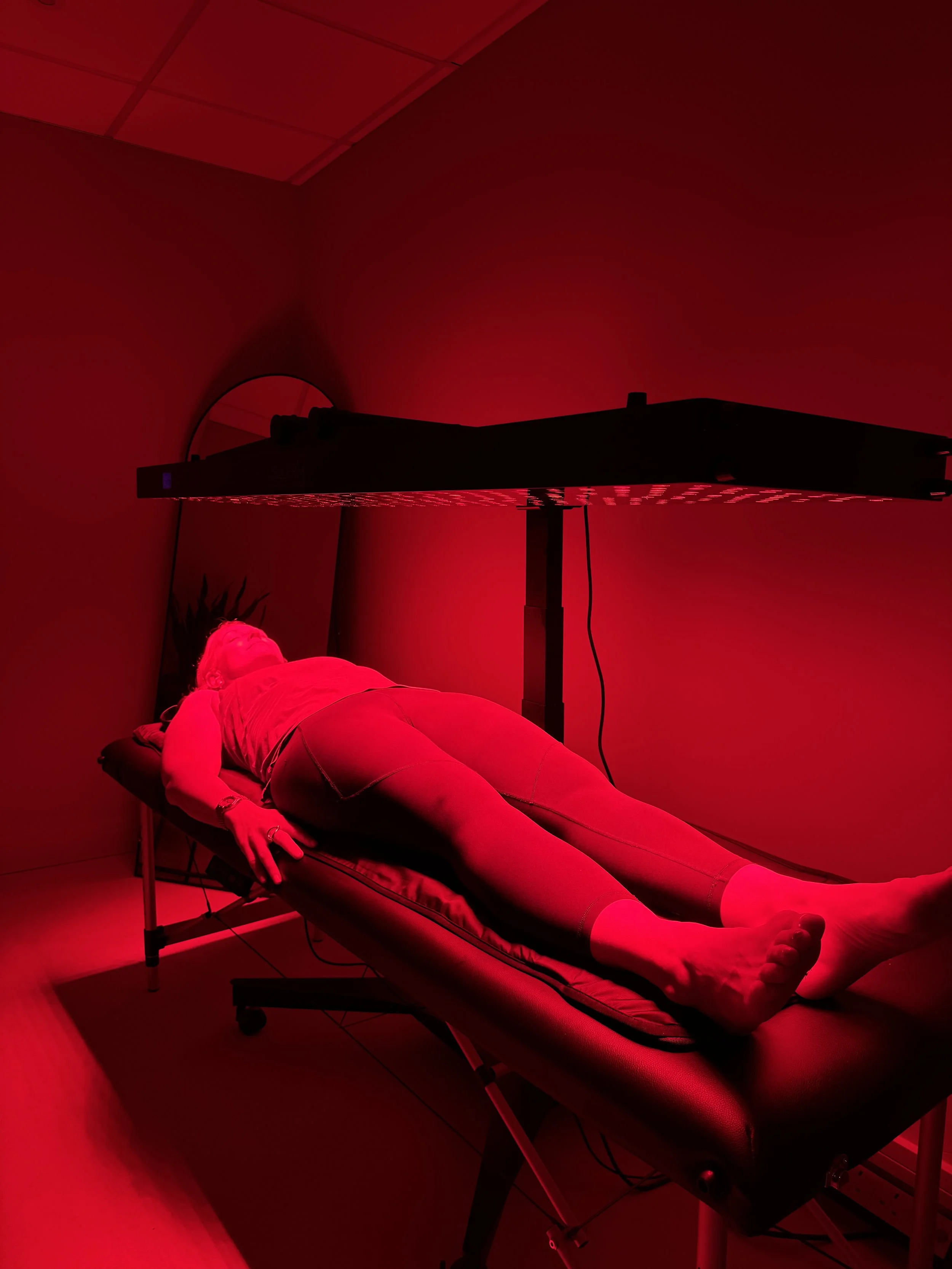 Client receiving red light therapy while lying on a treatment bed for chronic pain relief.