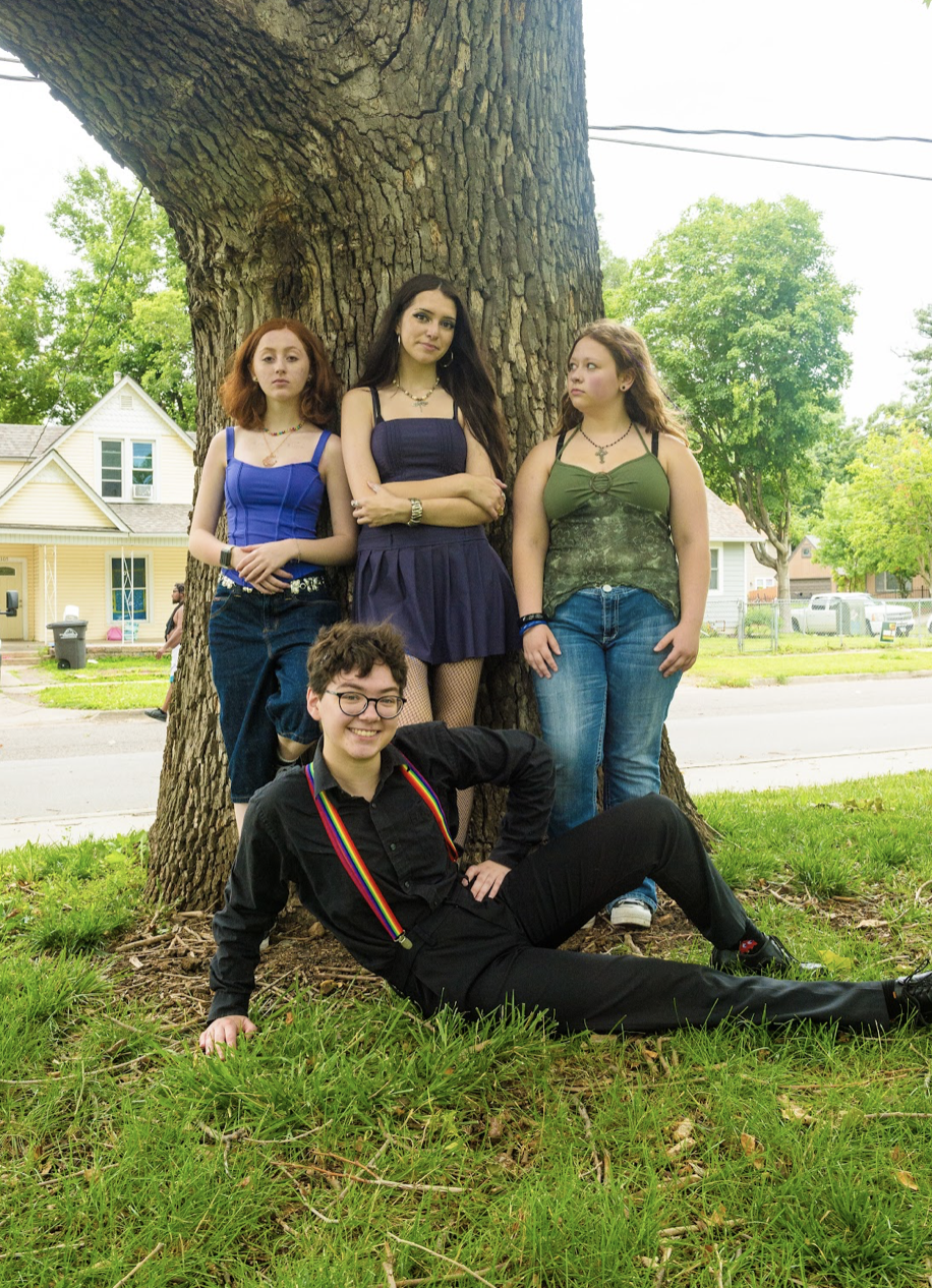 A Girls Rock Des Moines Summer Rock Camp youth band group photo leaning against a tree outside.