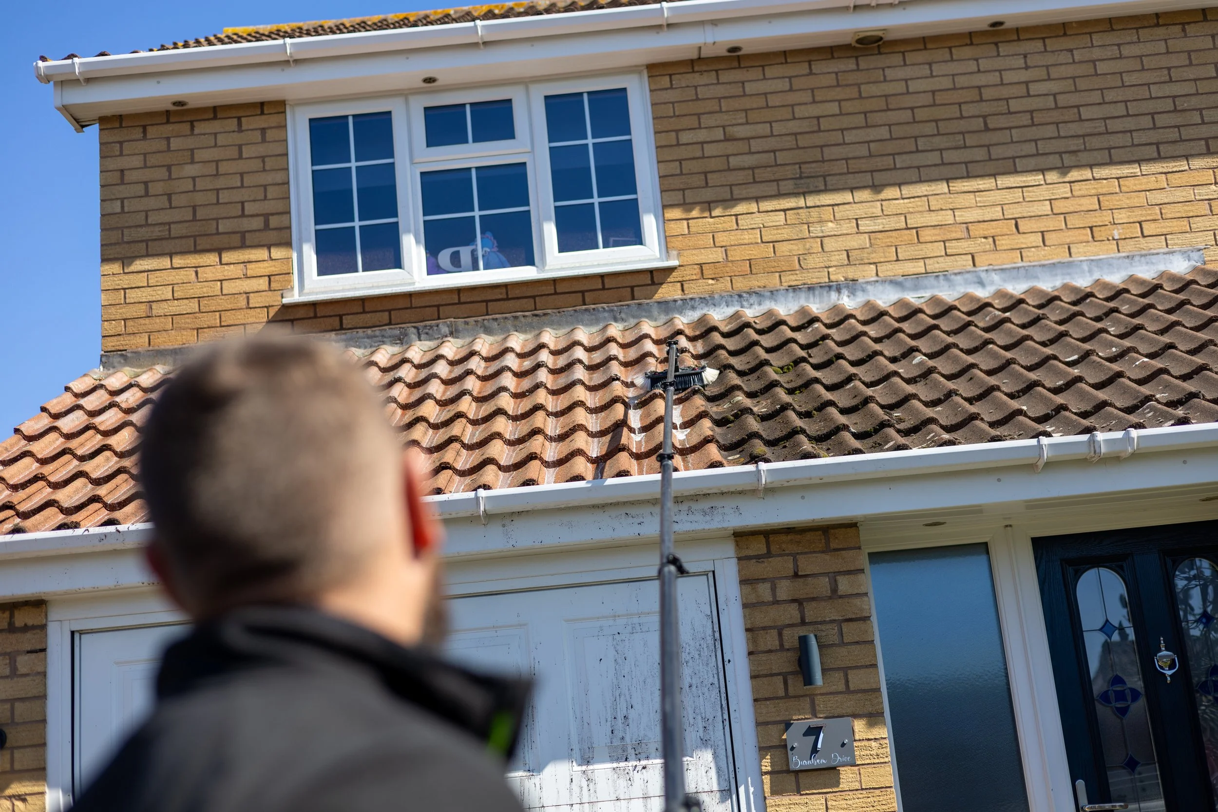 A brick house with a white conservatory extension and blue sky in the background.